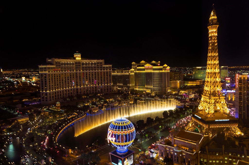 Las Vegas Strip at night with the Bellagio fountains, Paris Las Vegas Eiffel Tower, and resort towers along the boulevard.