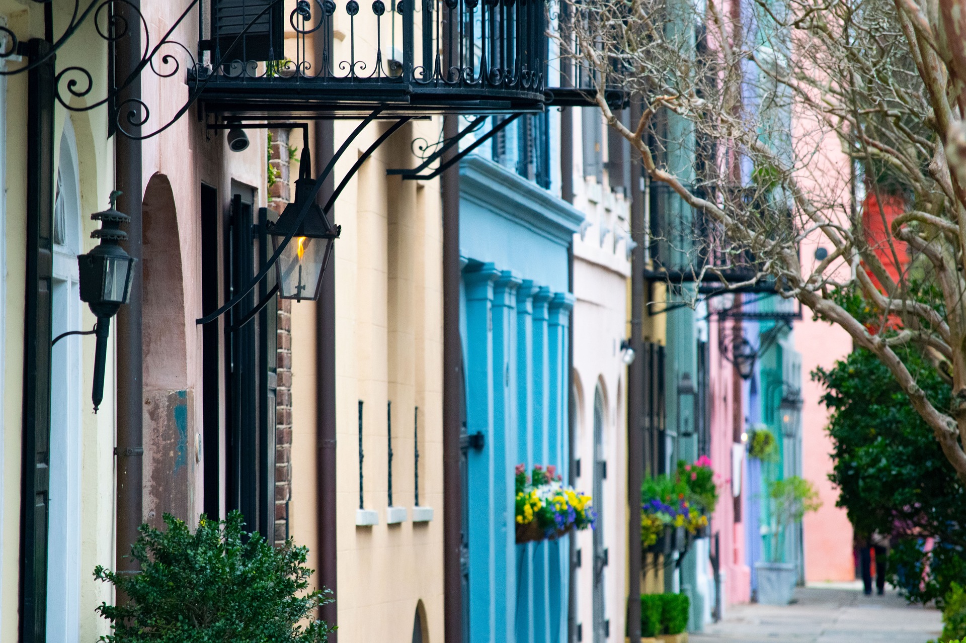 Pastel Charleston row houses with iron balconies along a quiet historic street.